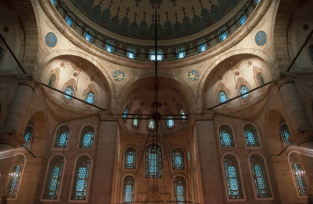 Interior of ornate mosque with stained glass windows.