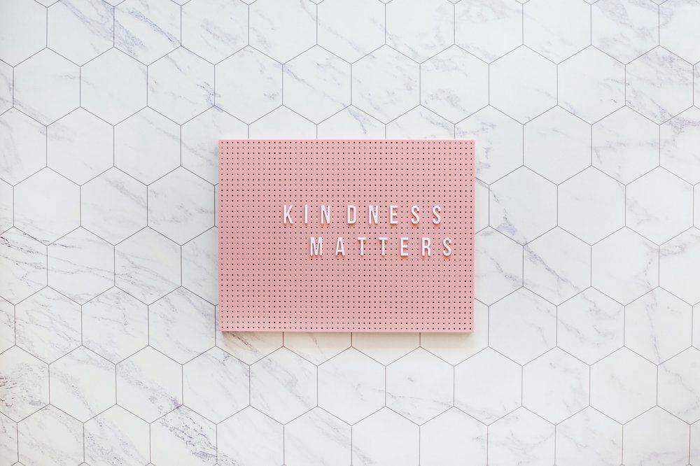 Pink sign saying kindness matters on hexagon tiles.