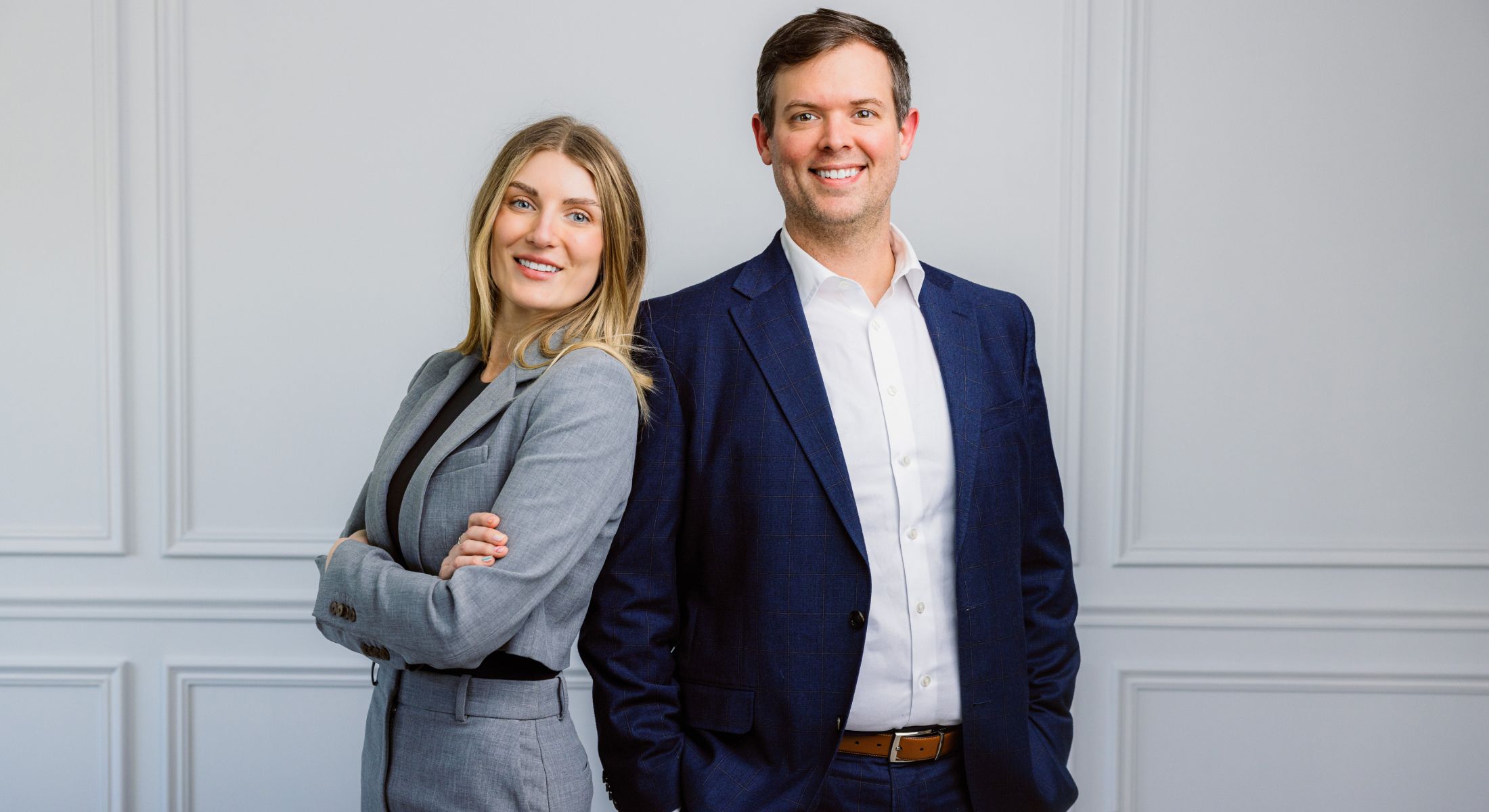 Professional couple posing in stylish office attire.
