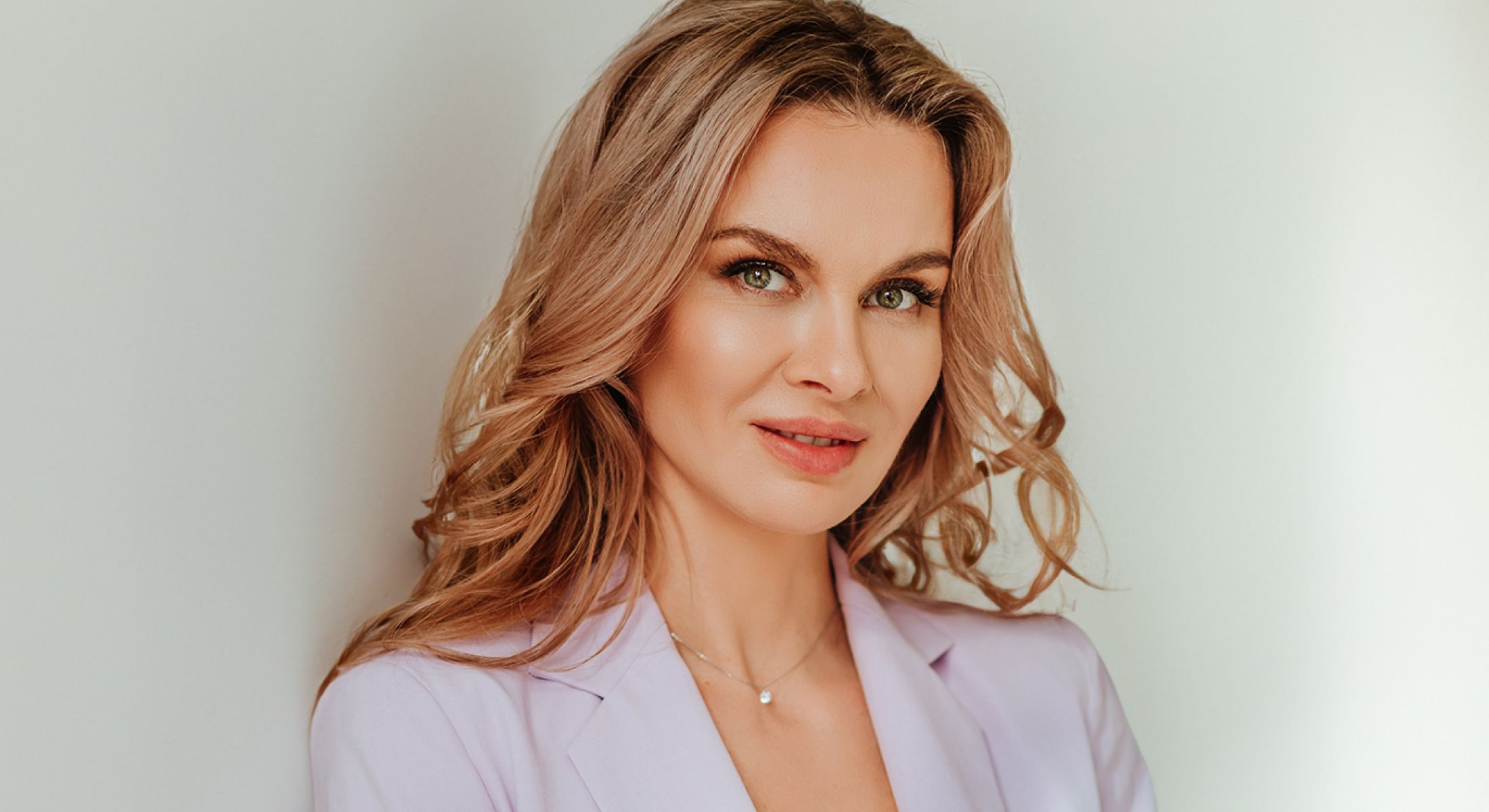 Confident Hinsdale dermal fillers model in a lavender blazer, smiling.