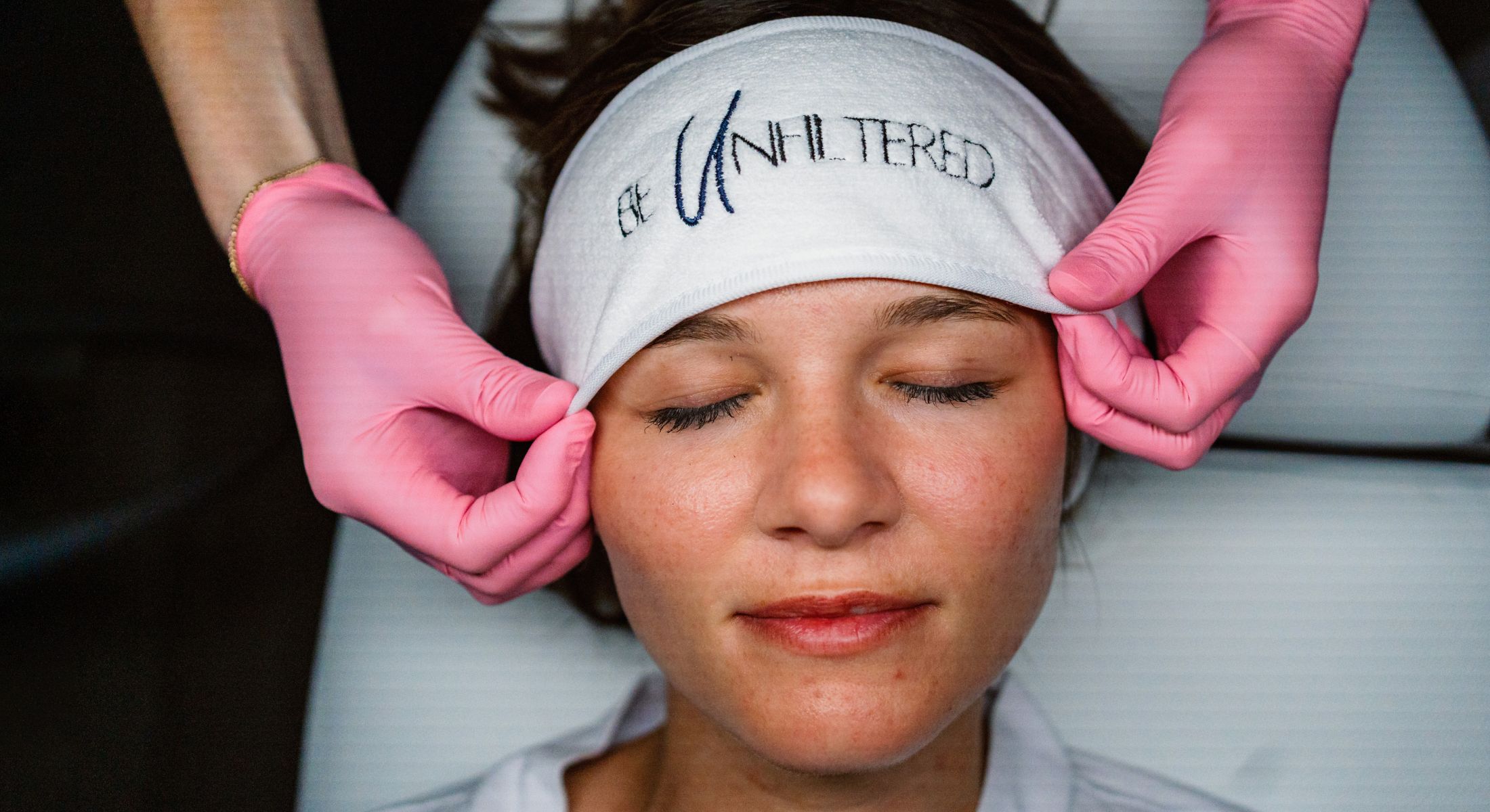 Facial treatment with pink-gloved hands.