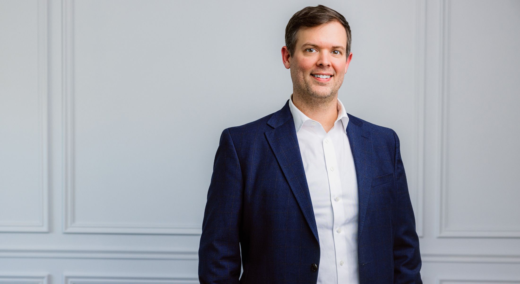 Man in suit against a light gray background.